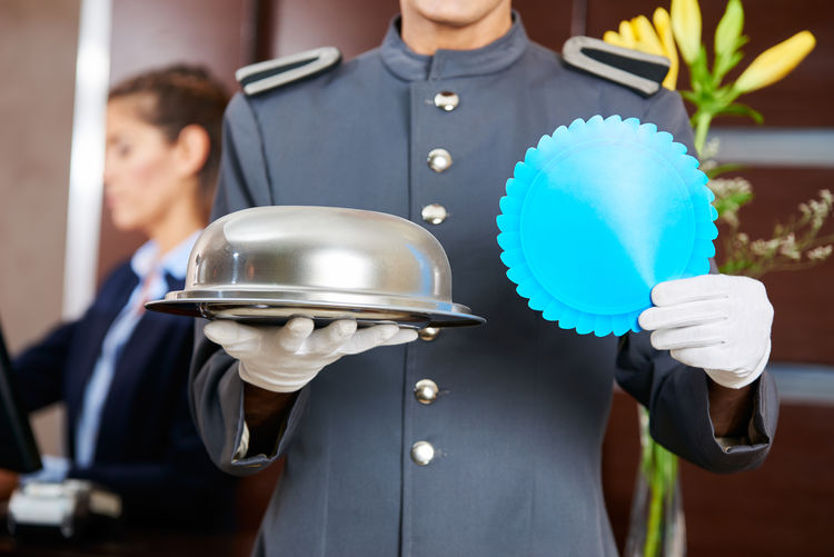 Midsection of waiter holding container in hotel