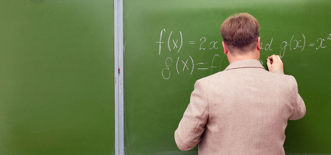 A math teacher shows students the solution of a problem at the school blackboard. copy space