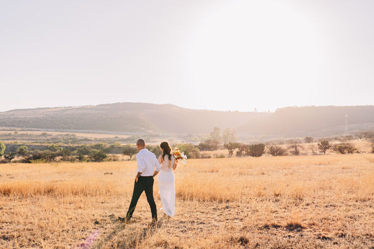 Couple standing on field against clear sky