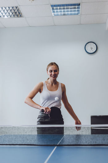 Smiling woman playing table tennis indoors
