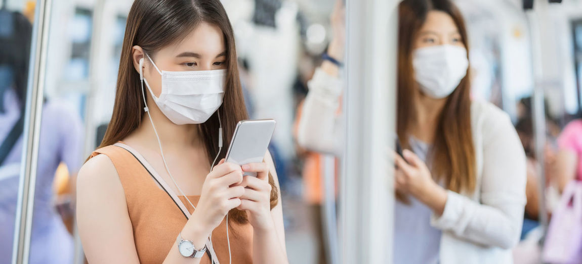 Woman wearing mask using mobile phone in train