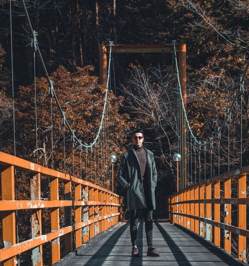 Portrait of young man standing on footbridge