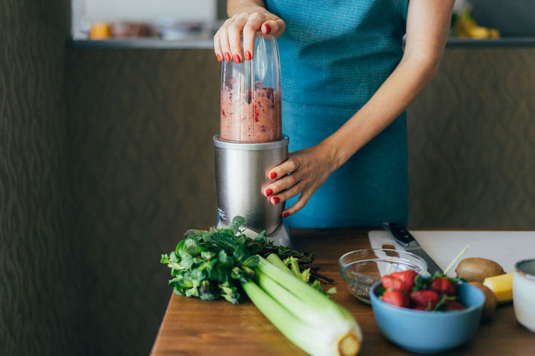 Close-up of a woman making a fruity summer pink smoothie. 