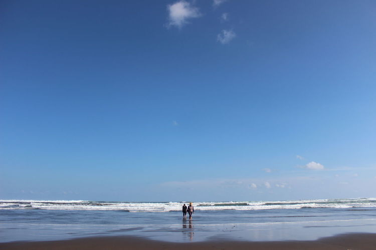 People walking at beach against sky