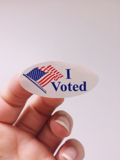 Cropped image of voting hand with american flag against white background