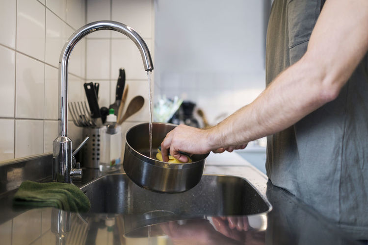 Midsection of man preparing food in kitchen at home