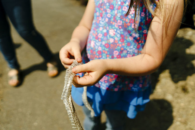 Cropped image of a young girl holding a found snake skin