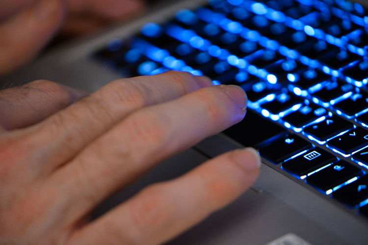 Cropped hand of man using laptop