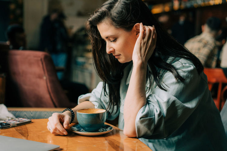 Beautiful brunette woman drinks coffee in a coffee shop.