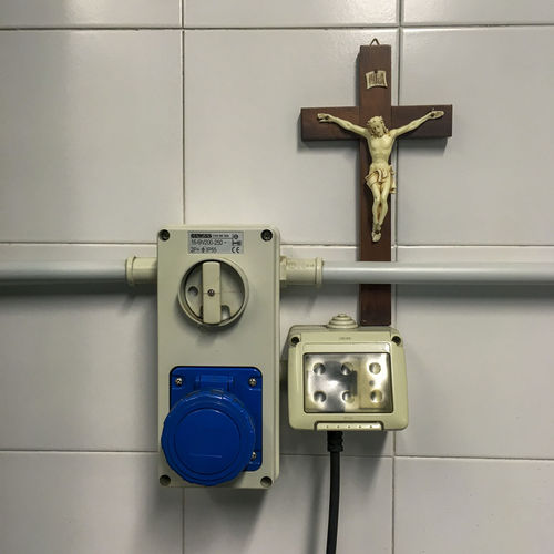 Close-up of cross and switch on wall