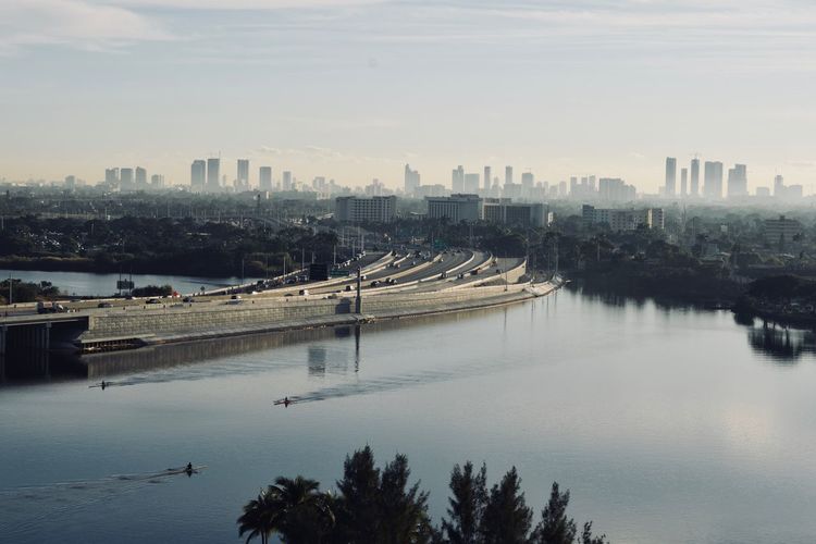 Scenic view of river by city against sky