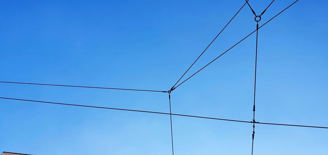 Low angle view of power lines against clear blue sky