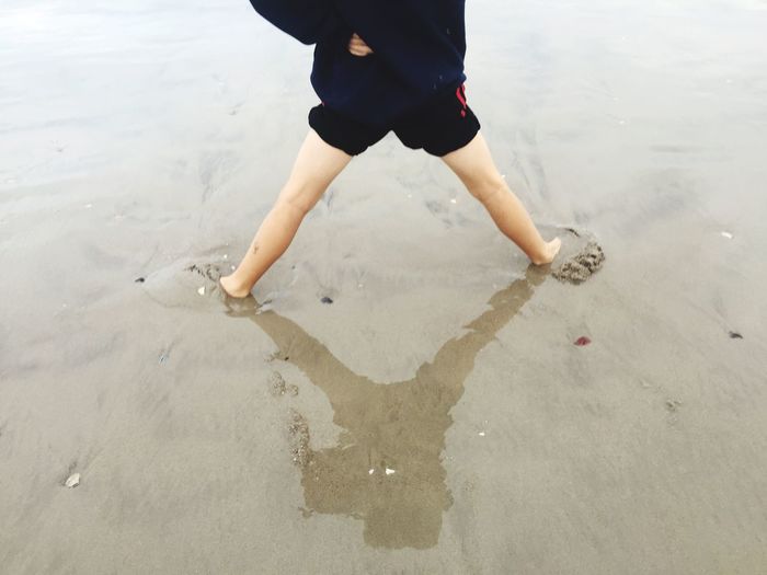 Low section of person standing at beach