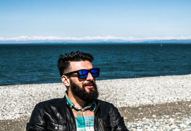 Portrait of man wearing sunglasses against sea against sky