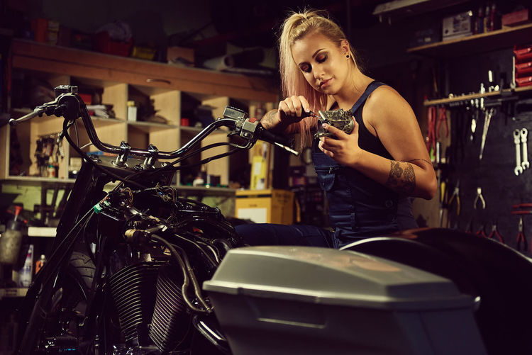 Beautiful mechanic repairing motorcycle in workshop