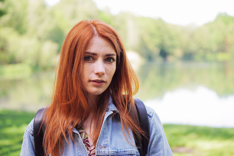 Portrait of beautiful young woman standing against lake