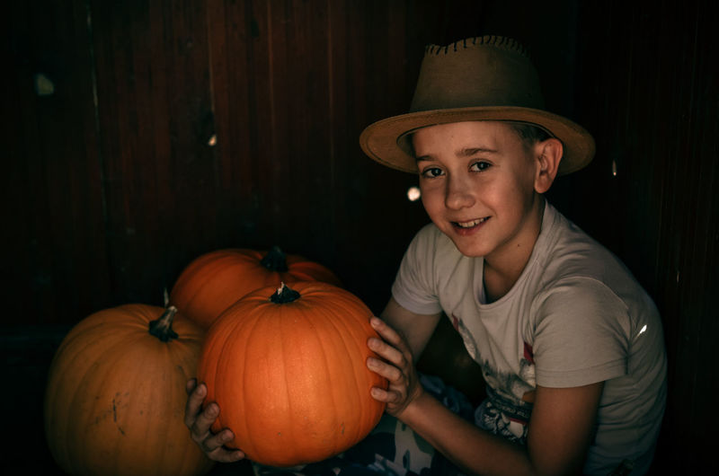 Portrait of smiling boy with pumpkins against orange background
