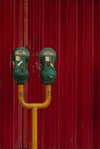 Concept photo of time is up or out of time- a red parking meter against bright red closed shutter.