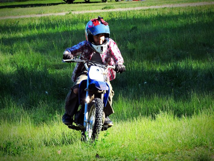 Boy riding motorcycle on grassy field