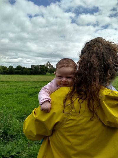 Portrait of cute girl with mother on field against sky