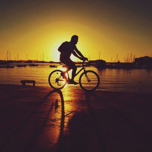 Man riding bicycle on water against sky
