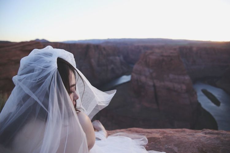 Bride wearing veil sitting on rock at glen canyon national recreation area