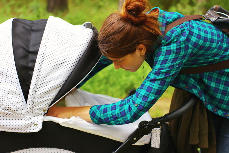 Side view of young woman with baby stroller outdoors