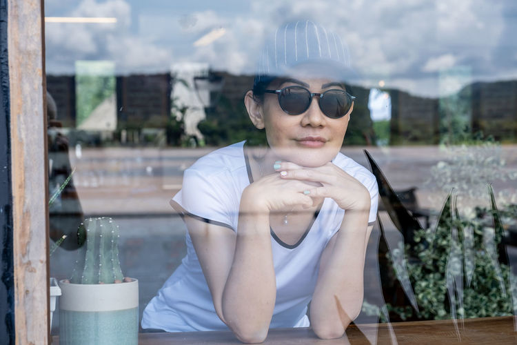 Portrait of young woman sitting on window