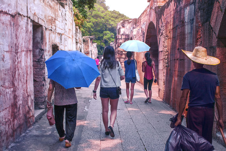 Rear view of tourists walking on footpath at historic building