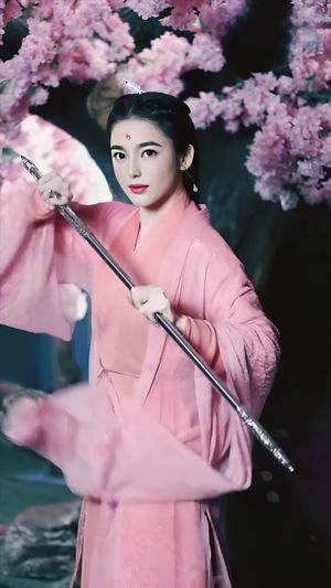 Portrait of a woman in japanese clothes holding a samurai in front of cherry blossoms