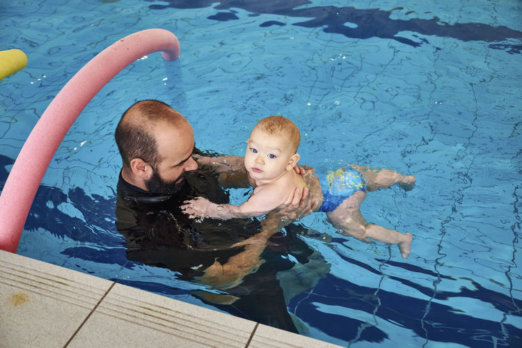 High angle view of man playing with son in swimming pool