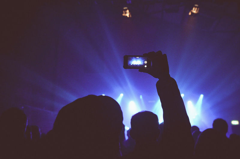 Rear view of silhouette person photographing during music concert