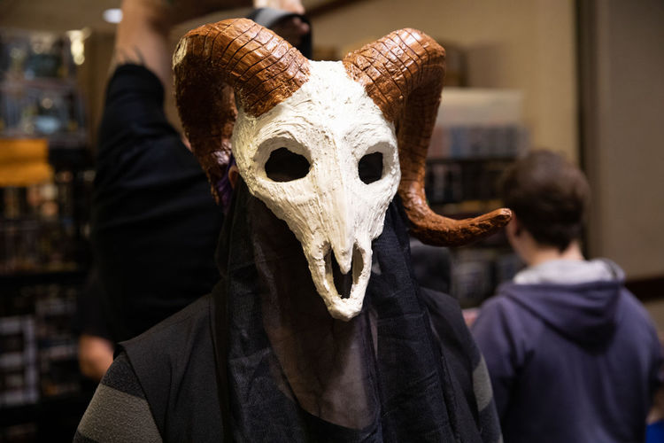 Close up portrait of a aries mask worn by a figure in black