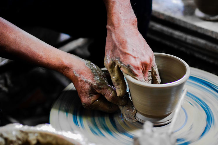 Cropped hands of man making pot in workshop