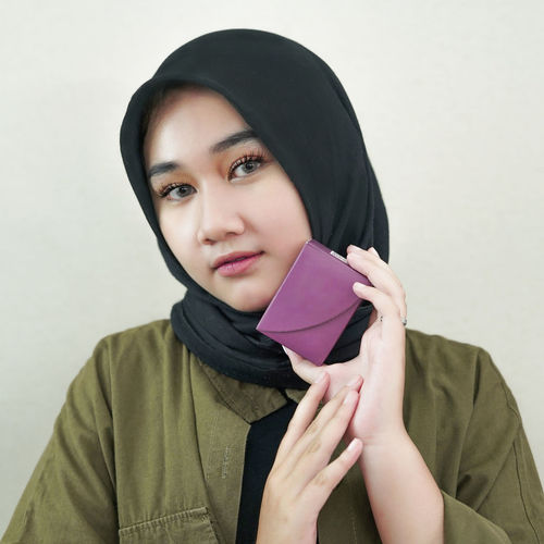 Portrait of young woman wearing hijab against white background
