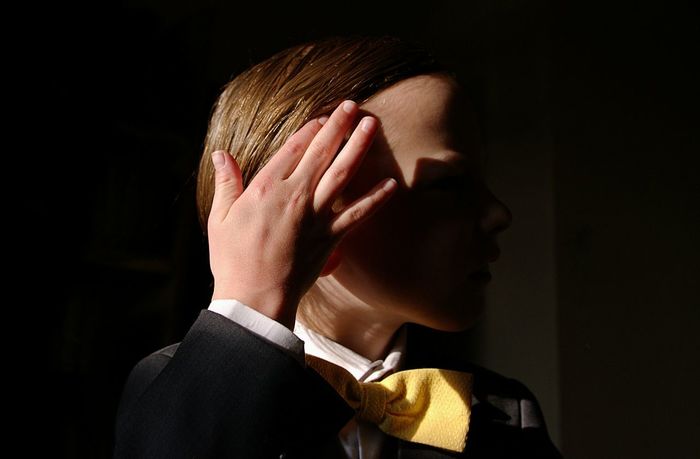 Close-up of boy with hand in hair against black background