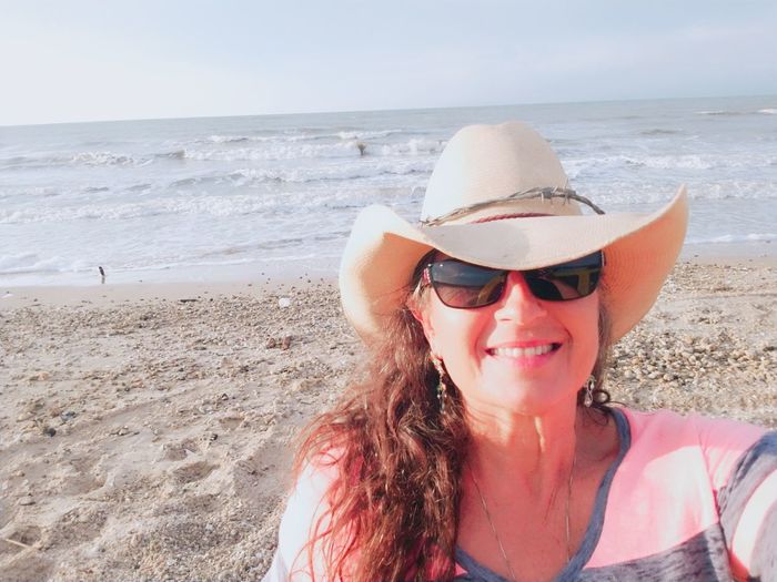 Portrait of smiling mature woman wearing hat at sandy beach