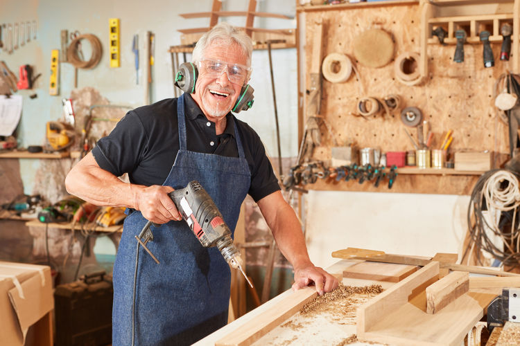 Portrait of senior carpenter holding drill at workshop