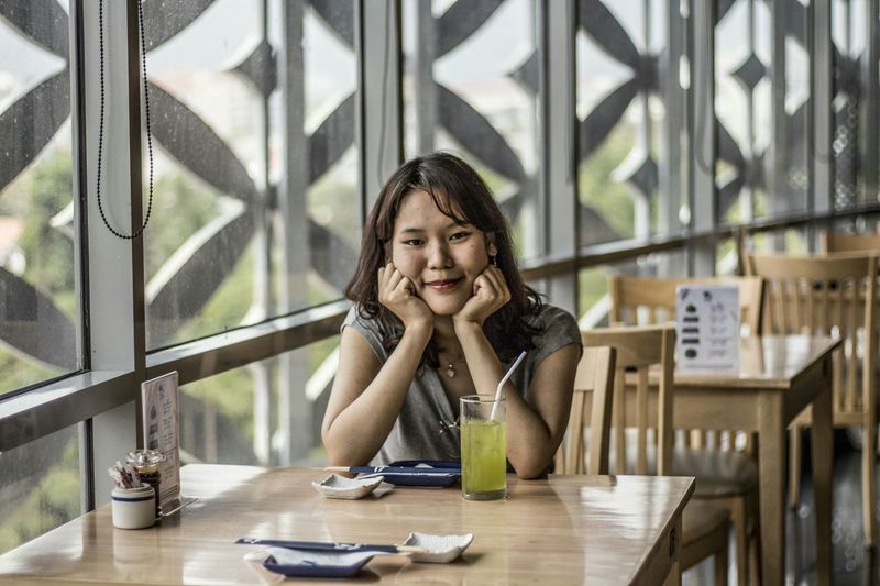 Portrait of young woman sitting on table in restaurant