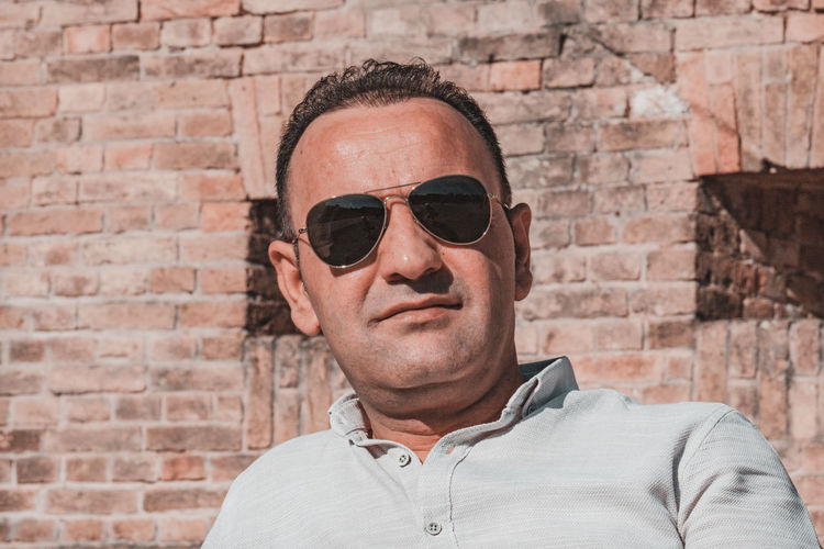 Smiling man wearing sunglasses against wall