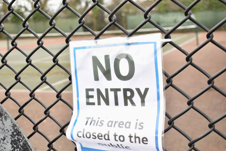 Close-up of warning sign on chainlink fence