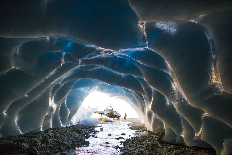 Helicopter parked outside of a glacial ice cave.