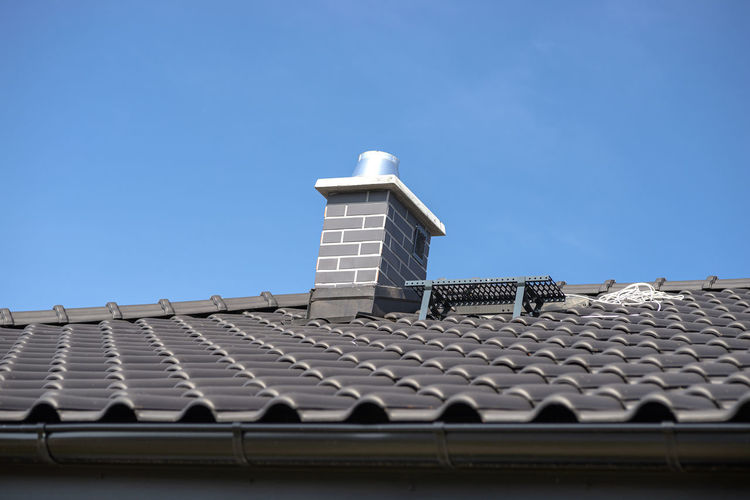 The roof of a single-family house covered with a new ceramic tile in anthracite, system chimney.