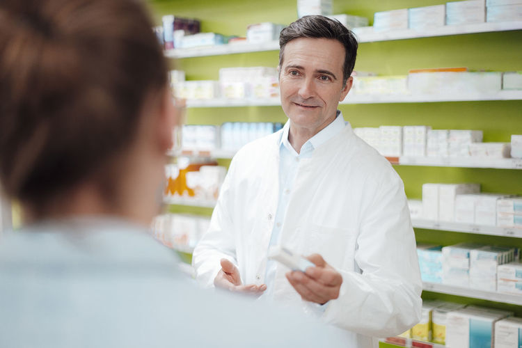 Pharmacist giving medicine to customer at pharmacy