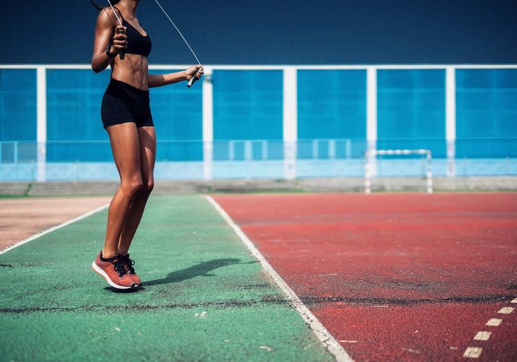 Woman rope skipping on a sports field