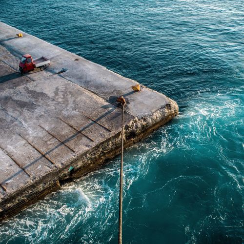 High angle view of rope tied on bollard by turquoise sea