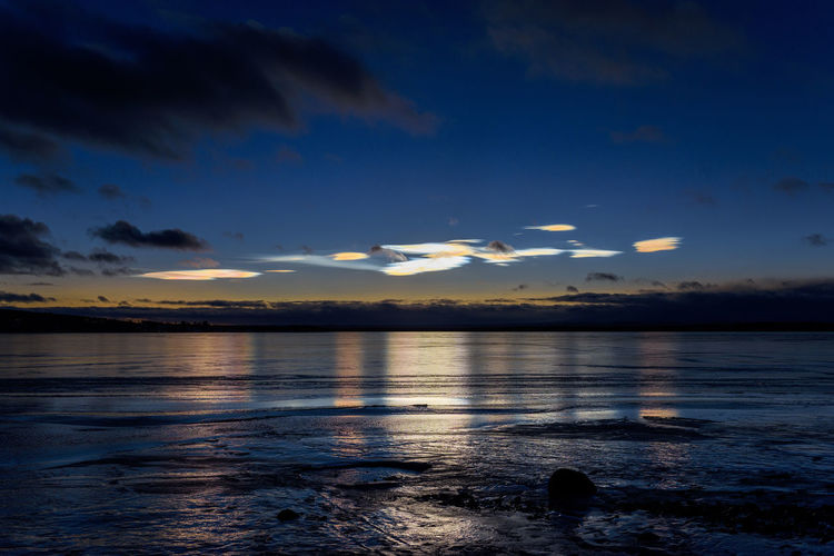 Scenic view of lake against  noctilucent clouds sky at sunset