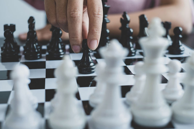 Cropped hand of woman playing chess