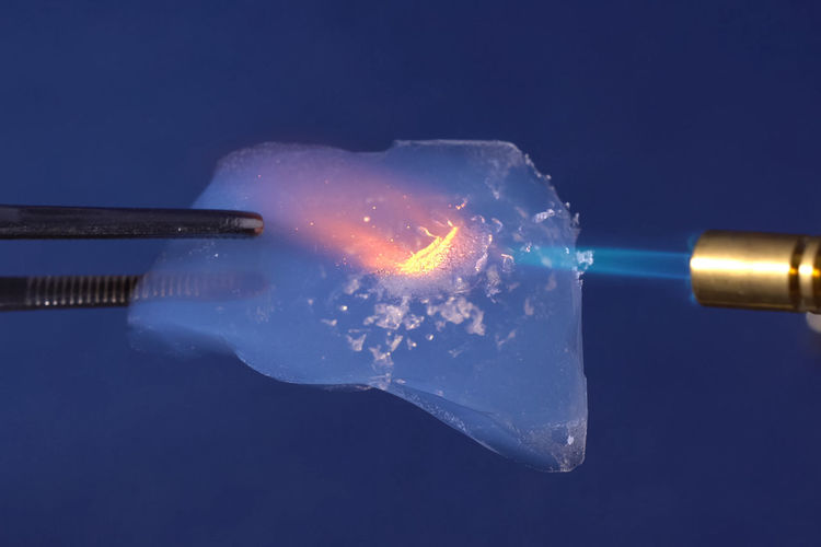 Close-up of welding torch burning plastic against blue background