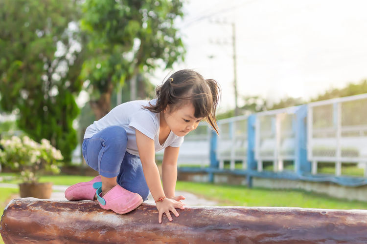 Full length of girl sitting on play equipment at park